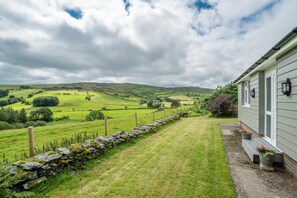 A rural landscape with a stone wall, a grassy path, and a house with a light-colored exterior and windows. - Hendre-Llangwm -  a self catering cottage that sleeps 5 guests  in 3 bedrooms (Llangwm)