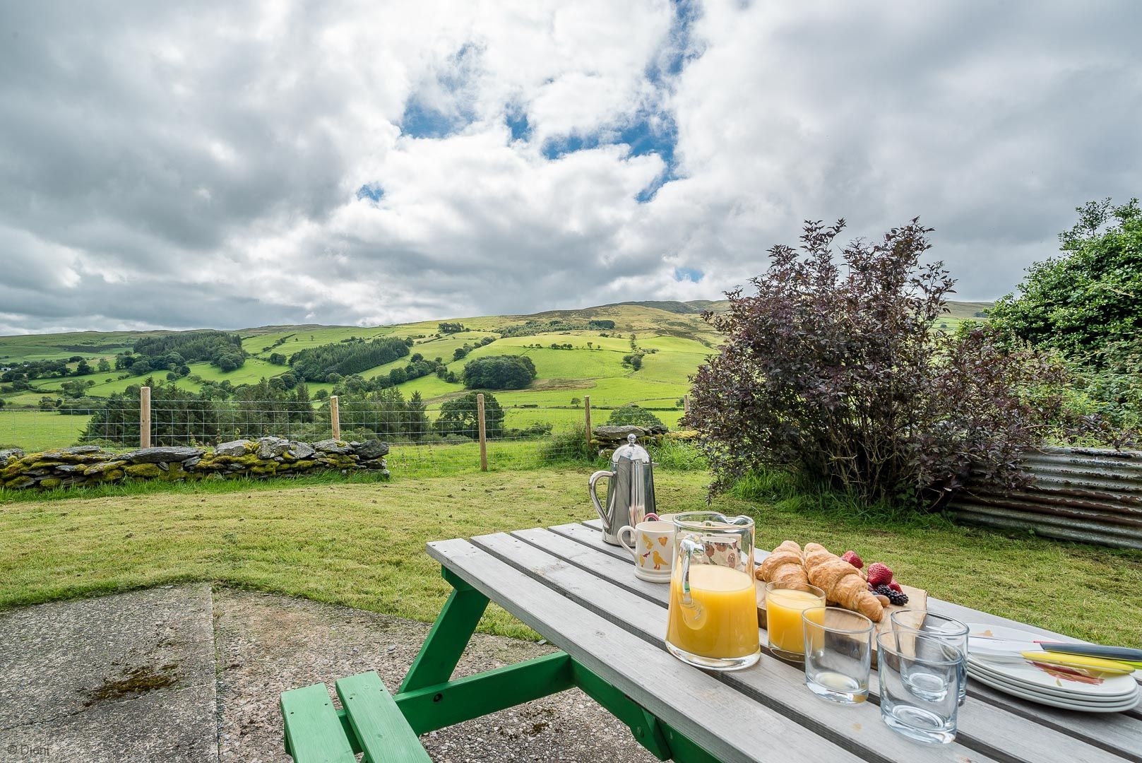 Ein Picknicktisch mit Blick auf sanfte Hügel und einen bewölkten Himmel.