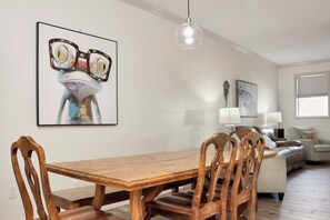 Ein Essbereich mit einem Holztisch, Stühlen, einem Bild an der Wand und einer modernen Pendelleuchte.