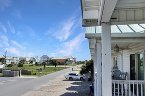 A residential street with houses, a parked white SUV, and a clear blue sky. - Steps to Beach | Great Location | Fenced in Yard | Mystic Nights by the Sea (Mexico Beach)