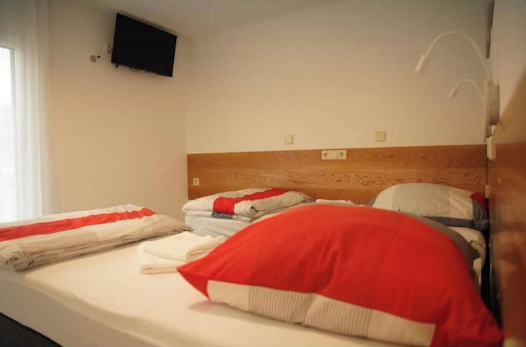 Een hotelkamer met een bed, een aan de muur bevestigde televisie en een houten hoofdbord.