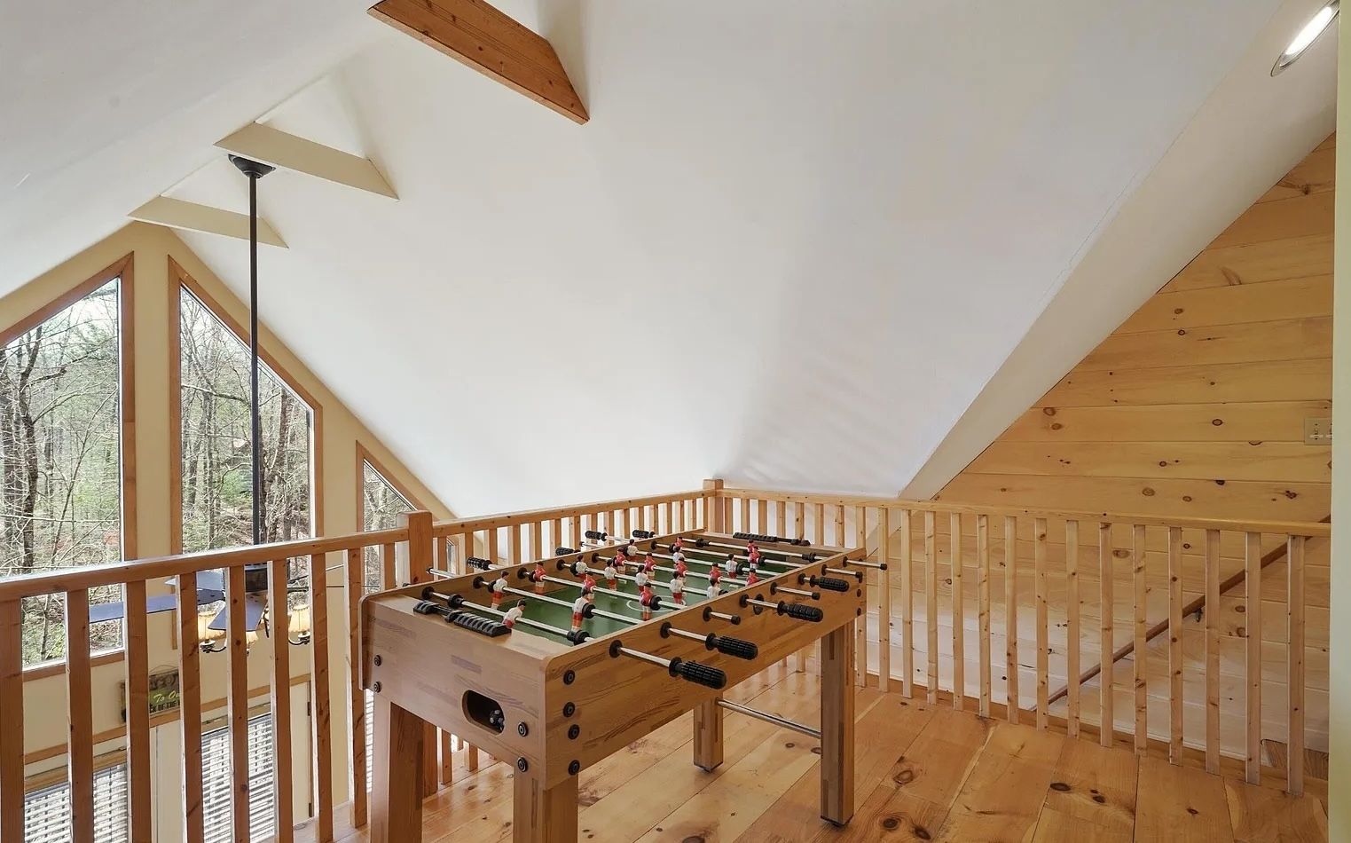 Un tavolo da calcio d'aria in una stanza con pavimento in legno e soffitto spiovente.