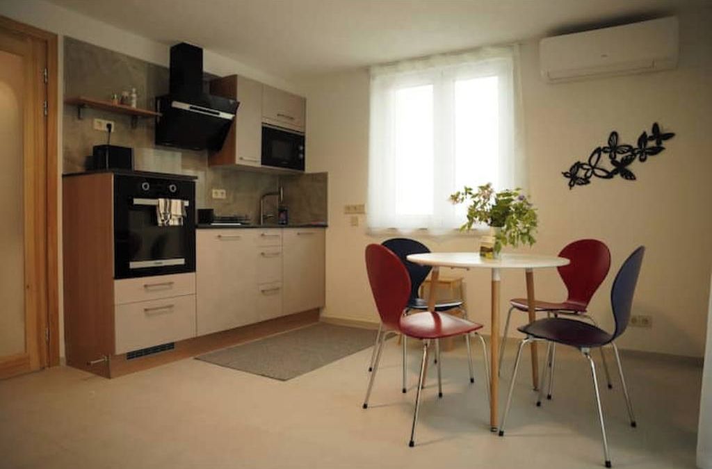 Ett kompakt kök med mikrovågsugn, ugn och en liten matplats med två stolar och ett bord.