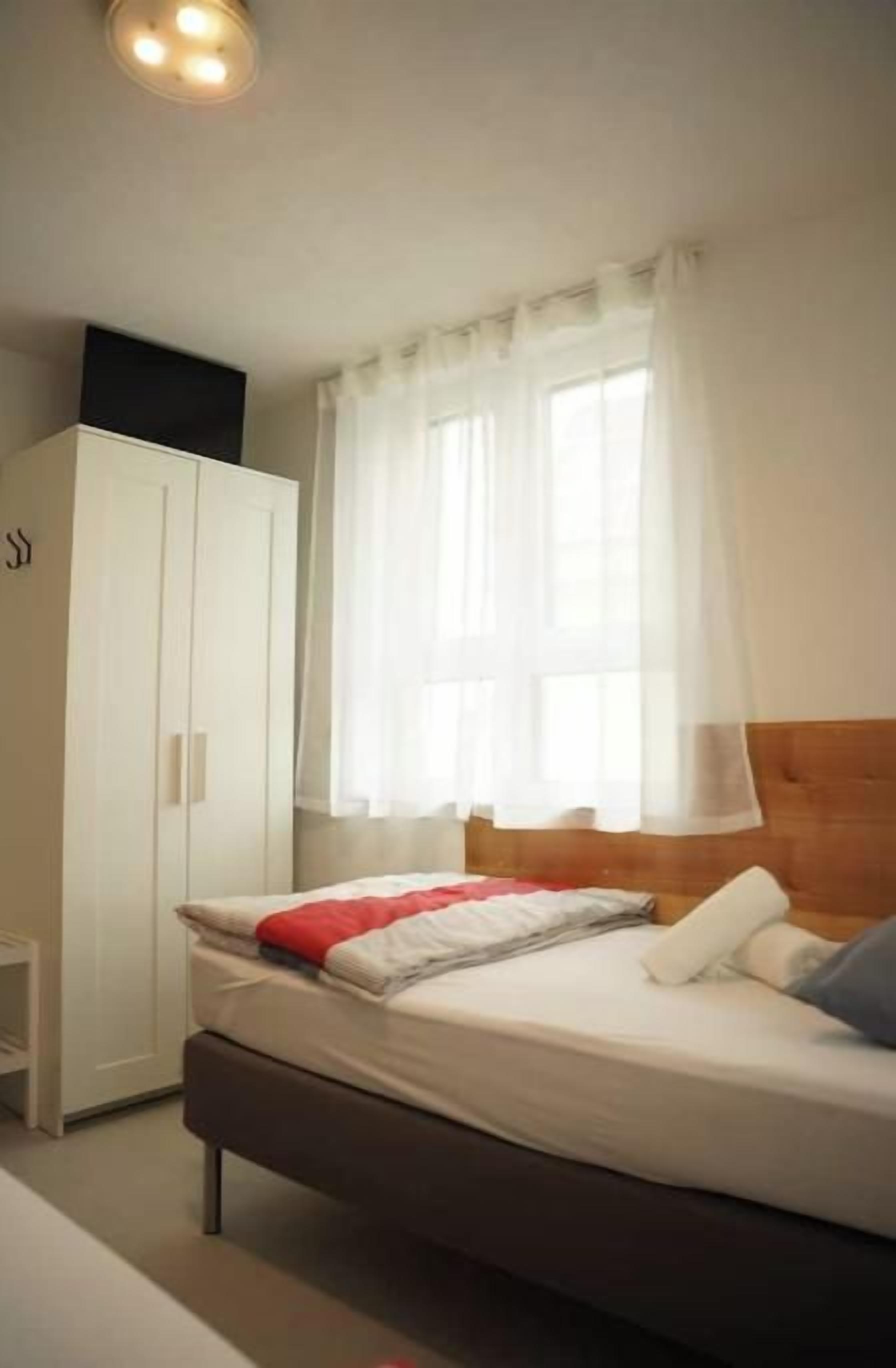 Een slaapkamer met een bed, een kledingkast en een raam met gordijnen.