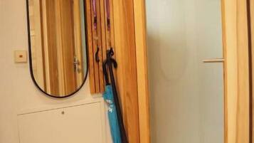 Ein Zimmer mit einer Holztür, einem Spiegel und einem Kleiderständer mit einem blauen Gegenstand darauf.
