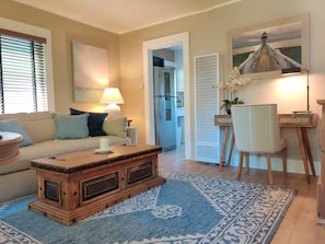 A living room with a sofa, a coffee table, a lamp, a chair, and a decorative wall piece. - Jackson's Cottage Retreat near Sony Studios (Culver City)