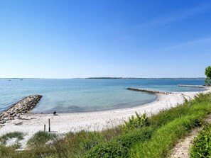 A coastal beach with clear water, a rocky breakwater, and a sandy shore. - 4 Star Holiday Home in Faaborg (Faaborg)