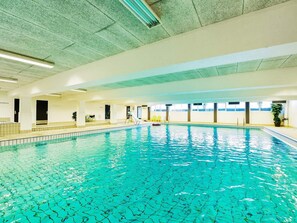 An indoor swimming pool with clear water, a slide, and a seating area with chairs. - 4 Star Holiday Home in Faaborg (Faaborg)