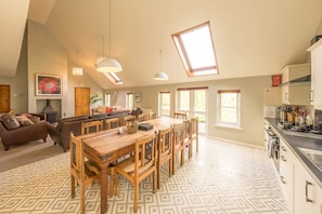 A spacious living area with a dining table, sofas, and a kitchen with a stove.