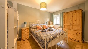 A bedroom with a bed, bedside tables, a wardrobe, and a hanging light fixture. - Pet Friendly Farm Stay with Hot Tub Pembrokeshire | Clematis-Y-Ffynnon (Pembrokeshire)