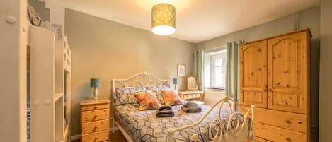 A bedroom with a bed, bedside tables, a wardrobe, and a hanging light fixture.