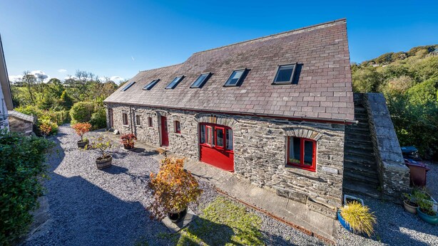 A stone building with a sloped roof and multiple windows, surrounded by gravel and potted plants. - Pet Friendly Farm Stay with Hot Tub Pembrokeshire | Clematis-Y-Ffynnon (Pembrokeshire)