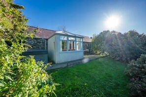A house with a stone facade, a conservatory, and a well-maintained garden. - Romantic stone cottage with hot tub in Pembrokeshire | Eiddew-Y-Ffynnon (Pembrokeshire)