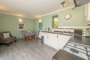 A compact kitchen with a dining area, featuring a gas stove, a microwave, and a sink.