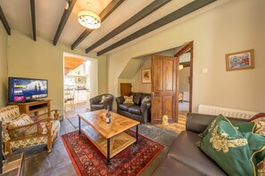 A living room with a television, sofas, a coffee table, and a patterned rug.