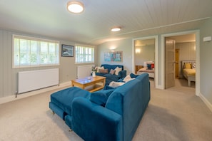 A living room with a blue sofa, a wooden coffee table, and a painting on the wall.