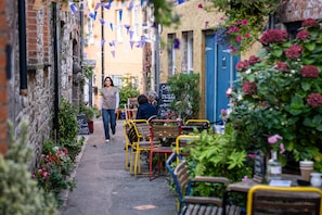 A narrow alley with outdoor seating, brick walls, and hanging flags. - Ffawydd-Y-Ffynnon -  a self catering cottage that sleeps 6 guests  in 3 bedrooms (Llanfyrnach)