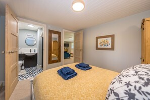 A bedroom with a bed, a bathroom with a toilet and sink, and a hallway leading to another room. - Ffawydd-Y-Ffynnon -  a self catering cottage that sleeps 6 guests  in 3 bedrooms (Llanfyrnach)