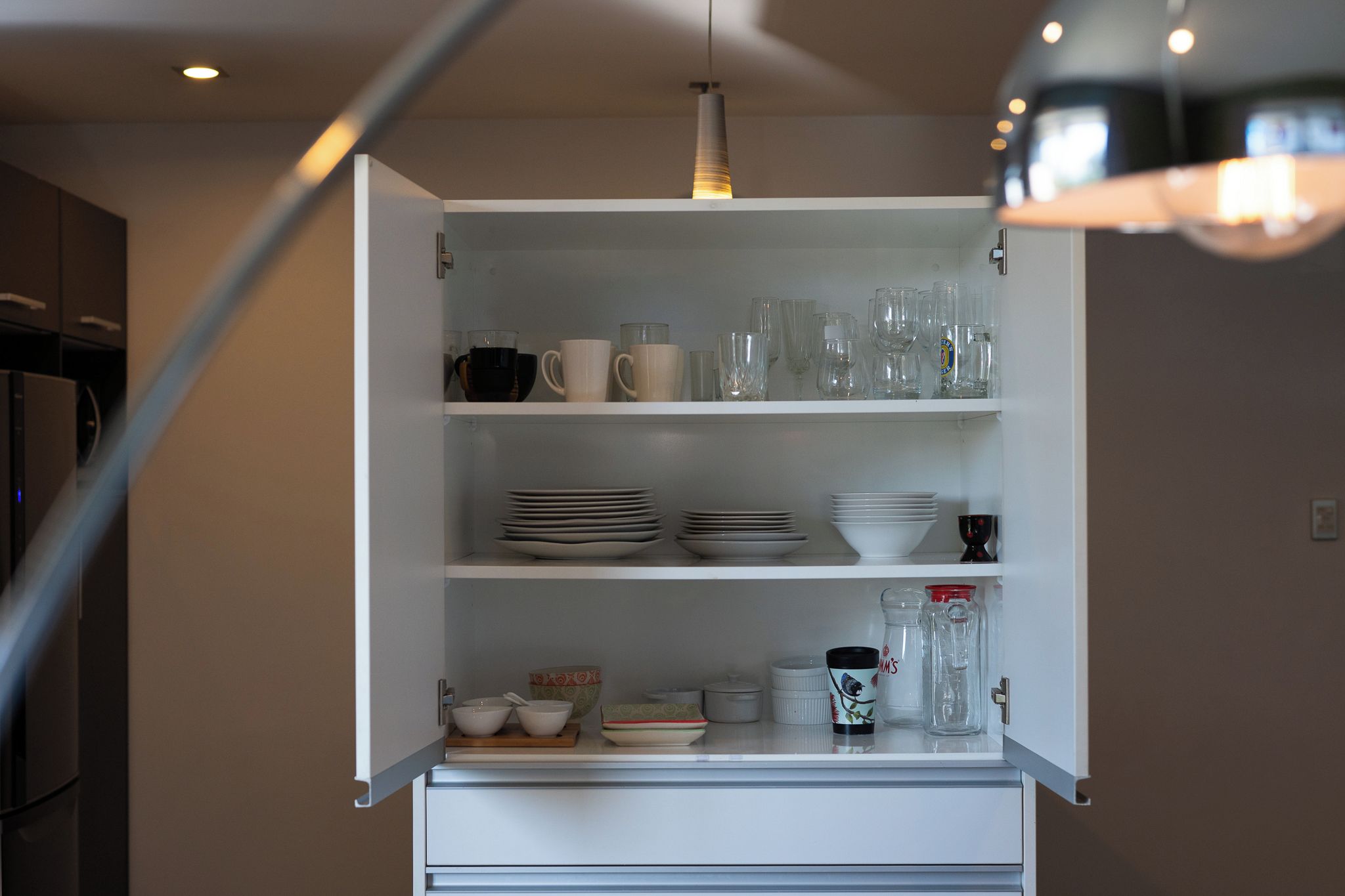 A kitchen with a white cabinet containing various dishes and glassware.