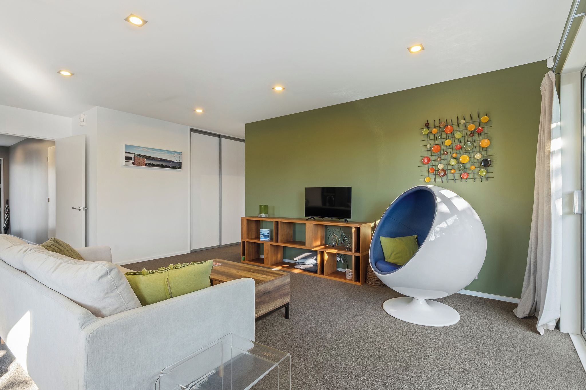 A modern living room with a sofa, a coffee table, a television, and a unique egg-shaped chair.