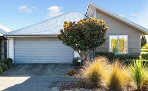 A residential house with a garage, a tree, and a well-maintained lawn.