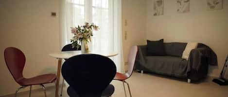 Un salon comprenant un canapé, deux fauteuils, une table et un vase avec des fleurs.