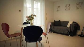 Ein Wohnzimmer mit einer Couch, zwei Sesseln, einem Tisch und einer Blumenvase.