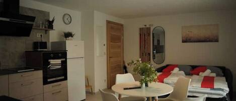 A compact living space with a kitchenette, a dining area, and a bed.