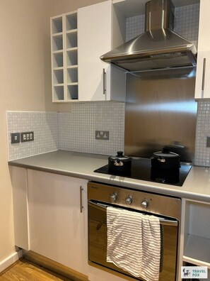 A compact kitchen with a stove, oven, and a stainless steel range hood. - Central Birmingham Flat with Free Parking! (West Midlands)