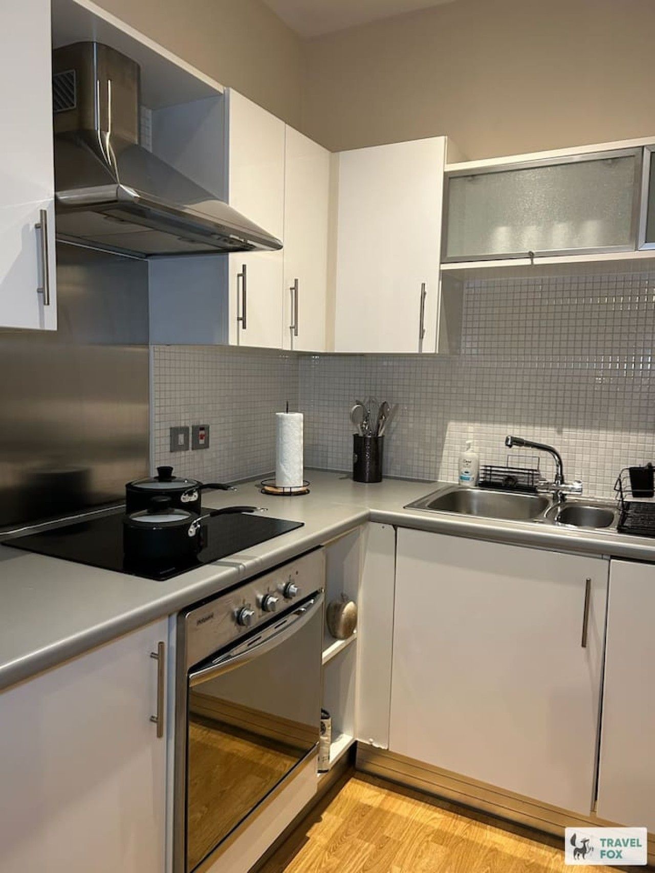 Una cocina moderna con electrodomésticos de acero inoxidable, armarios blancos y salpicadero de azulejos.