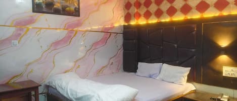 A bedroom with a bed, a nightstand, a wall-mounted telephone, and a framed picture.