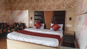 Habitación de hotel con una cama grande, cabecera con motivos florales y pared estampada.