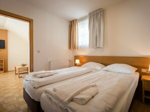 Une chambre d’hôtel avec un lit double, une table de chevet avec une lampe, une tête de lit en bois, un radiateur et un téléviseur fixé au mur.