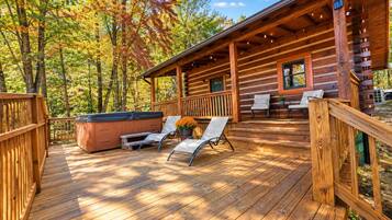 A wooden deck with outdoor seating and a hot tub.
