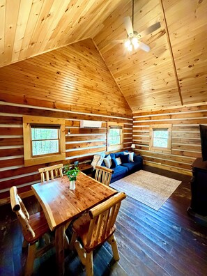 A wooden cabin interior with a dining table, chairs, a sofa, and a ceiling fan. - NEW LISTING PROMO Sunset Bluff Overlook Cabin in the RRG•
Hot Tub• Fireplace (Pine Ridge)
