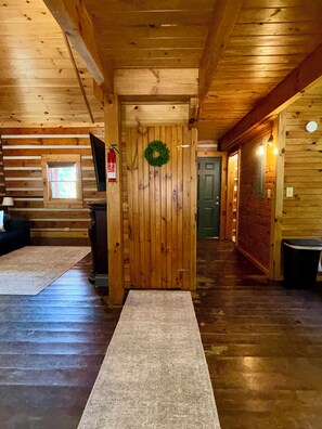 Un intérieur en bois avec une porte centrale, un couloir et une fenêtre.
