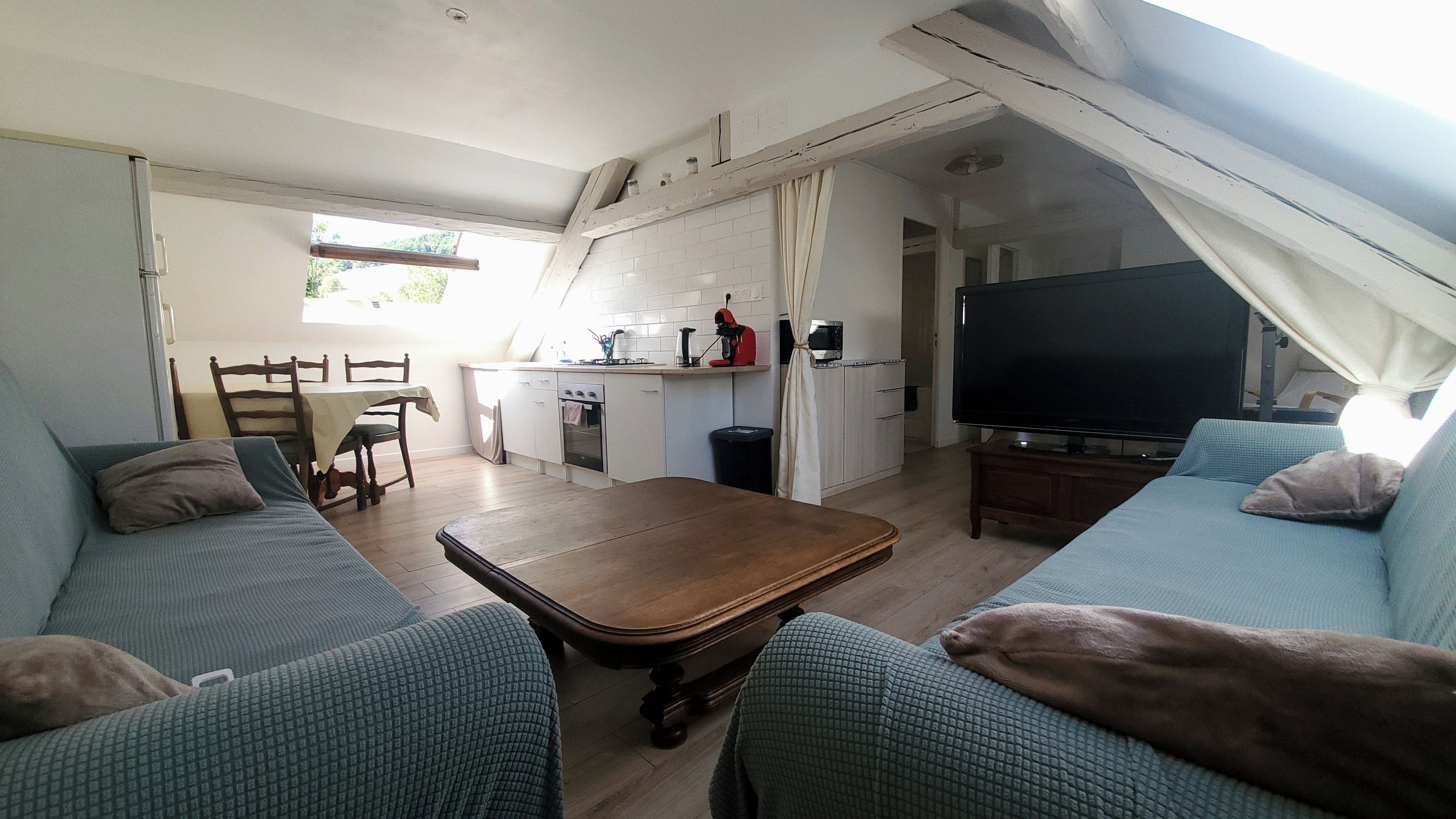 Un espacio habitable compacto con kitchenette, comedor, sofá y televisor.