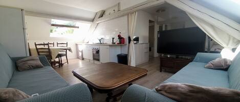Un espacio habitable compacto con kitchenette, comedor, sofá y televisor.