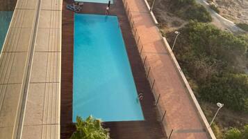 Ein Pool mit Blick auf den Ozean, umgeben von einer Holzterrasse und einem Pflasterweg.