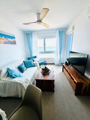 A room with a bed, a TV, a wooden coffee table, and a ceiling fan.