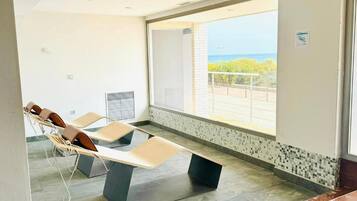 Un espace d’attente moderne avec vue sur la mer, un comptoir d’accueil et un coin salon avec des chaises.