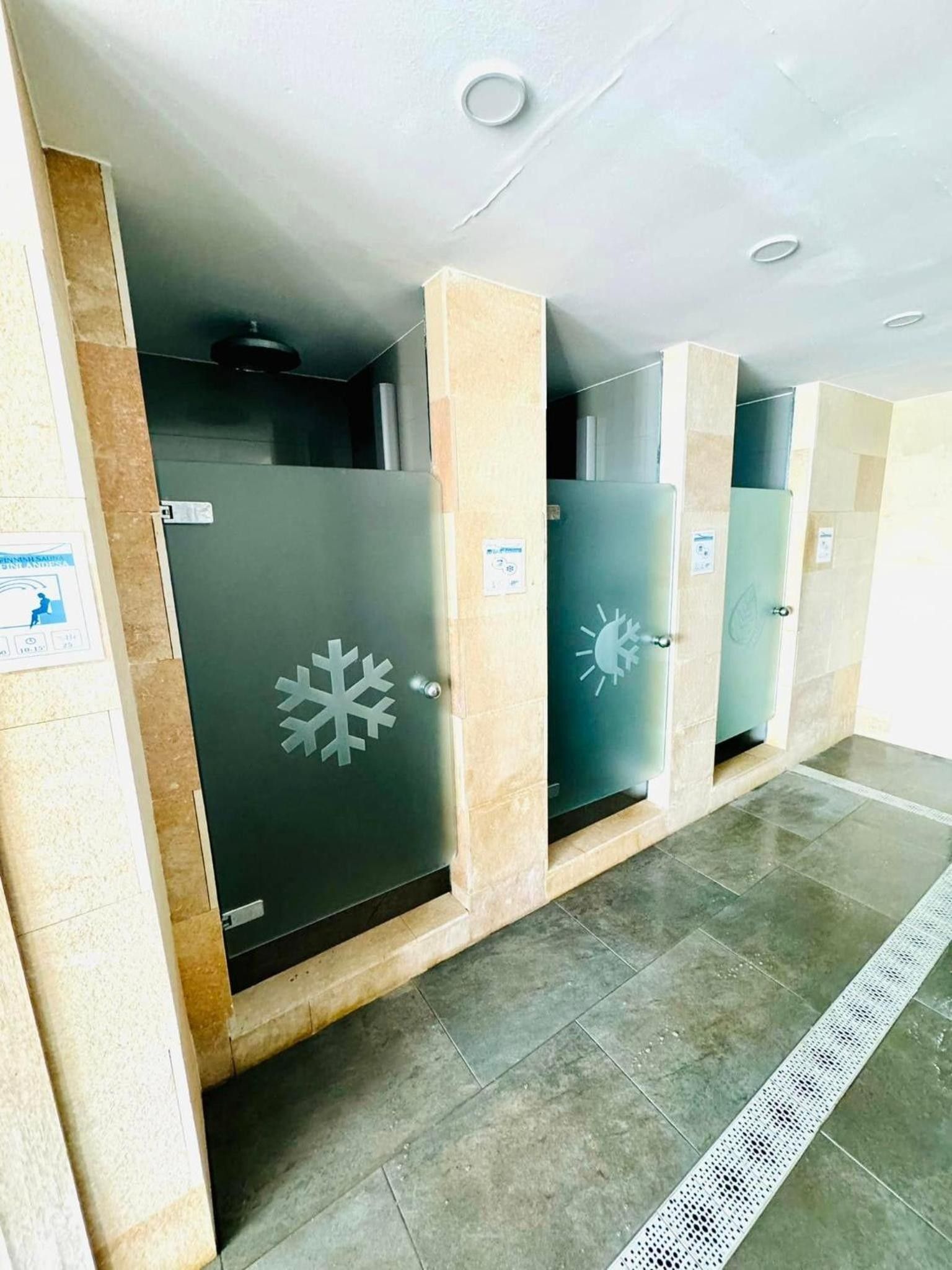 Eine Reihe von privaten Umkleidekabinen mit satinierten Glastüren, jede mit Schneeflockendesign.