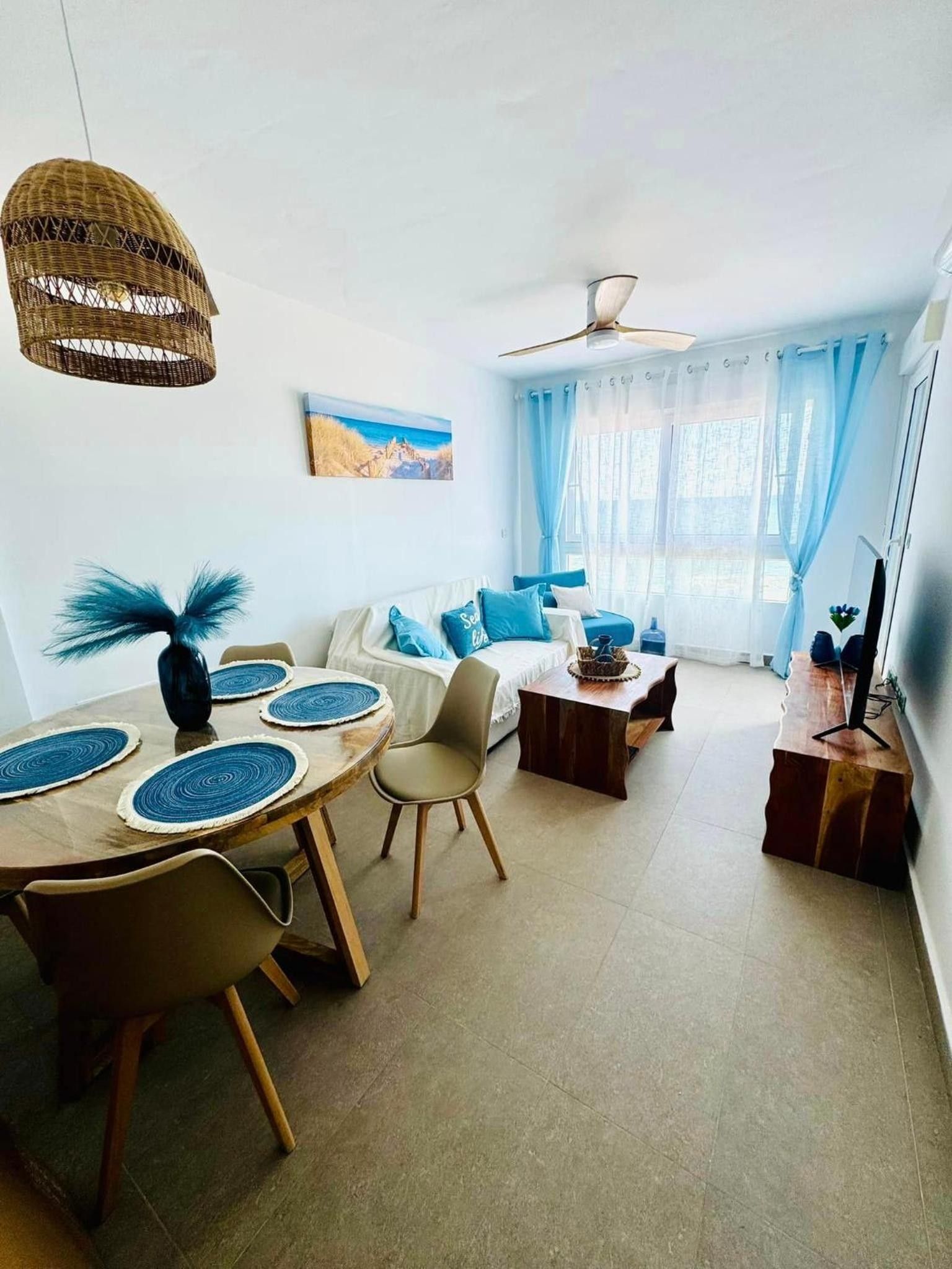 Ein modernes Wohnzimmer mit Essbereich, Deckenventilator und einem Gemälde an der Wand.