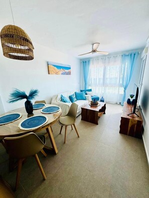 Ein modernes Wohnzimmer mit Essbereich, Deckenventilator und einem Gemälde an der Wand.