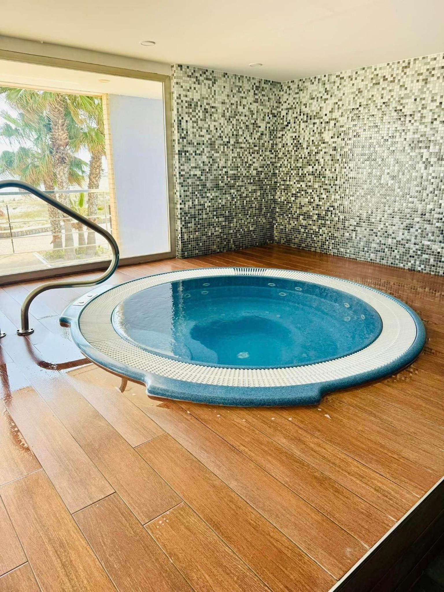 Ein Whirlpool mit einer gefliesten Wand und Holzboden.