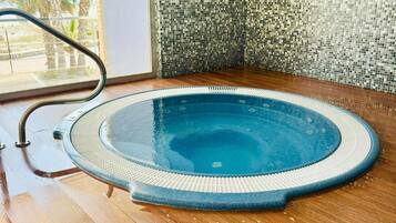 Ein Whirlpool mit einer gefliesten Wand und Holzboden.