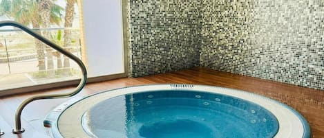 Una vasca idromassaggio con parete piastrellata e pavimento in legno.