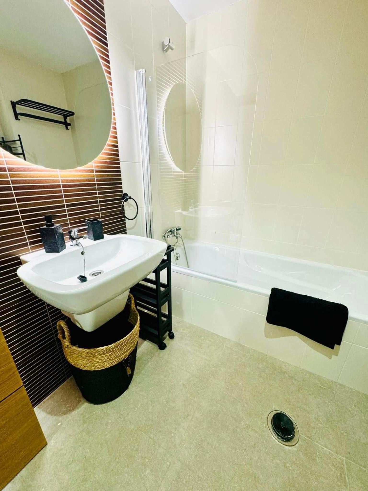 Ein Badezimmer mit Waschbecken, Handtuchhalter in Schwarz und einer Badewanne.