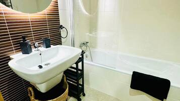 Ein Badezimmer mit Waschbecken, Handtuchhalter in Schwarz und einer Badewanne.