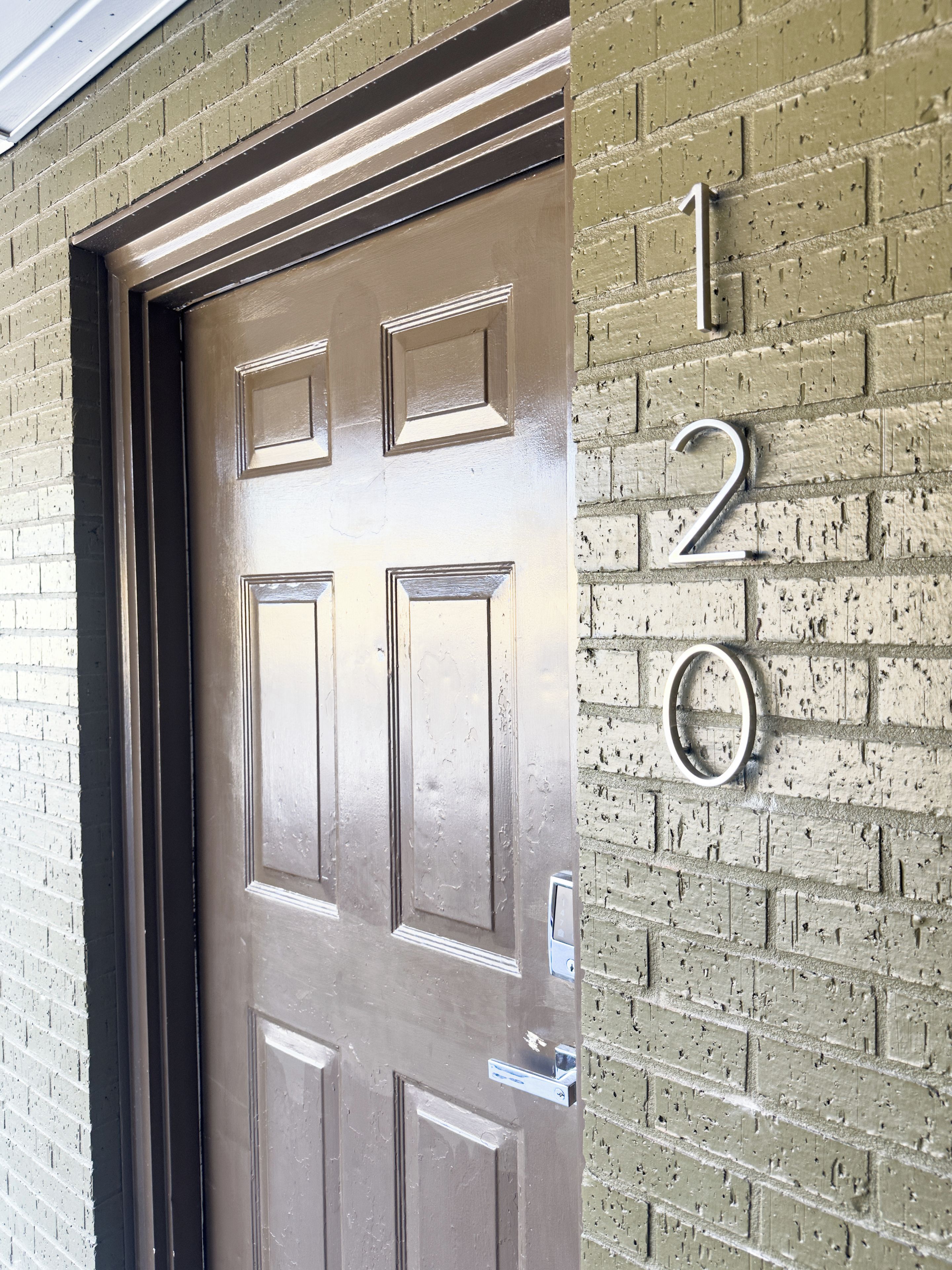 A door with a number '120' on a brick wall.